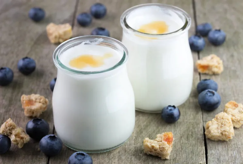 white yougurt in glass bowls on natural wooden table