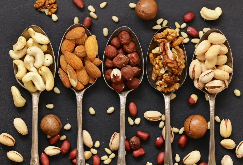 various kinds of nuts (cedar, cashew, hazelnuts, walnuts) in spoons