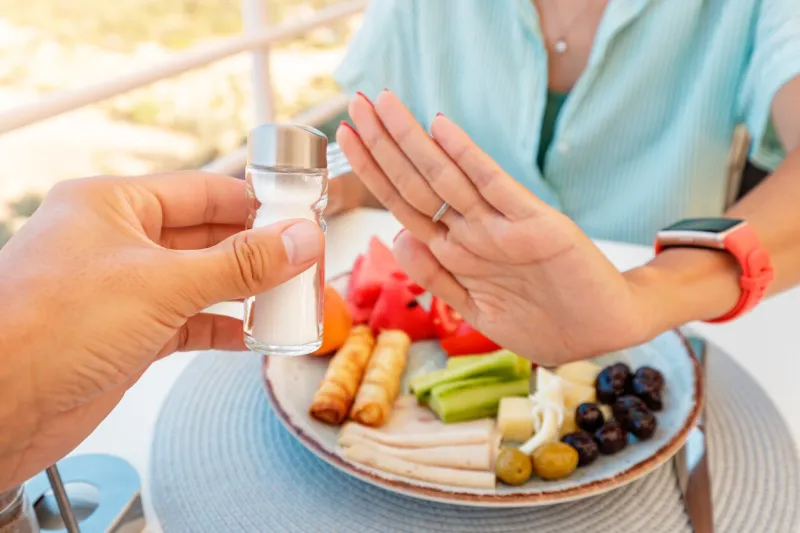 woman in a restaurant refuses the offered salt and pepper shaker with a gesture of her hand diet for gout and high cardiovascular blood pressure