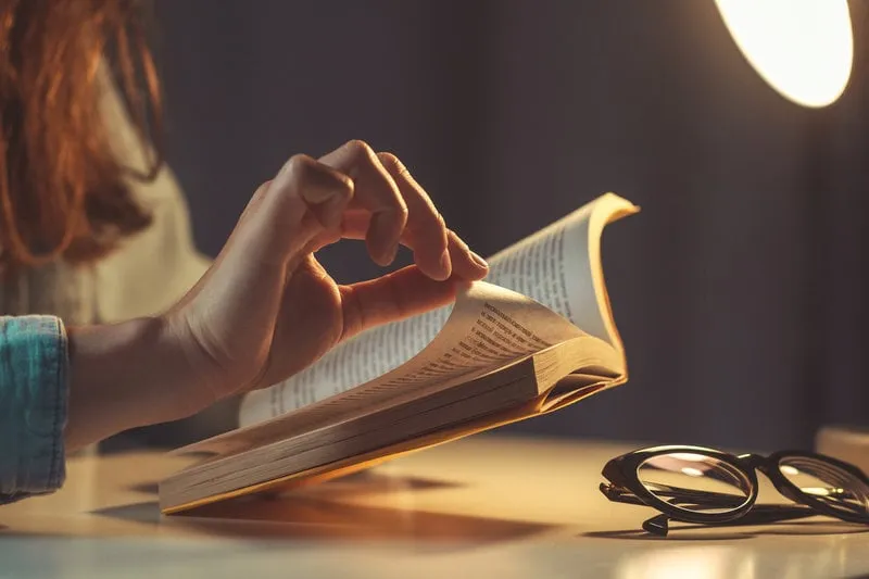 woman reading book at evening at home close up