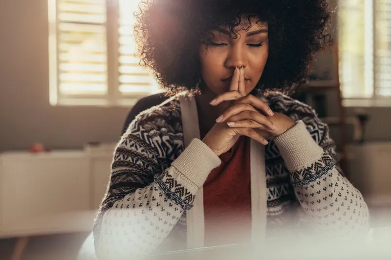 african female sitting at her work desk and thinking with her eyes closed stressed woman taking a break to come up with solution using mindfulness