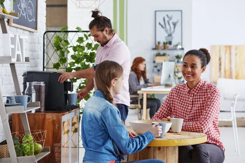 smiling coworkers drinking coffee in cozy relax zone