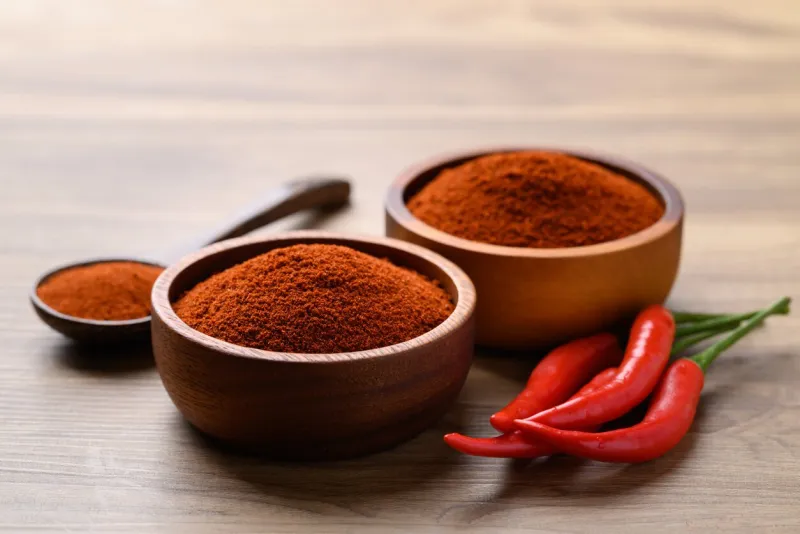 red chili powder in bowl on wooden background, food seasoning