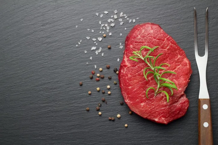 steak cru avec du sel et du poivre sur la plaque d'ardoise