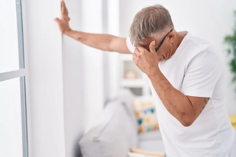 middle age grey-haired man suffering dizzy standing at home