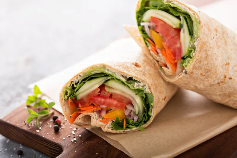 vegan vegetable wrap with lettuce, cucumber and tomatoes sliced in half
