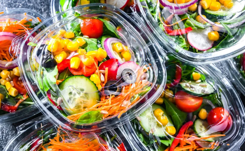 plastic boxes with pre-packaged vegetable salads, put up for sale in a commercial refrigerator
