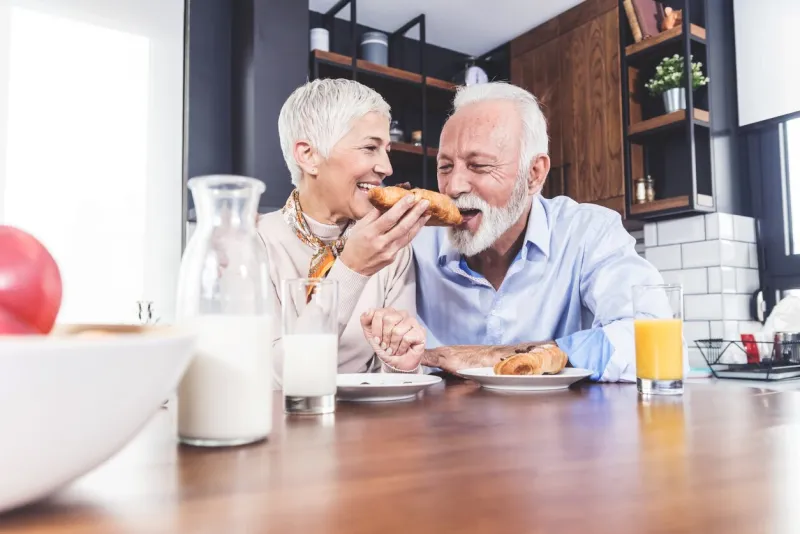 senior couple enjoying their time at home, in kitchen with breakfast in the morning closeup picture with copy space