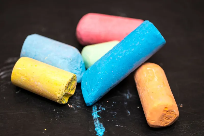 tas de crayons de couleurs différentes sur un tableau noir de fond noir