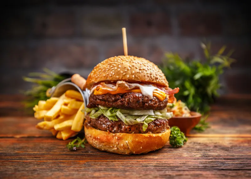 fresh tasty burger and french fries on rustic wooden table