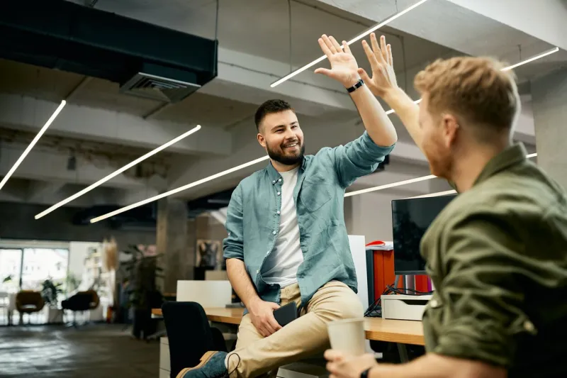 happy entrepreneur and his colleague give high five while congratulating each other on well done job