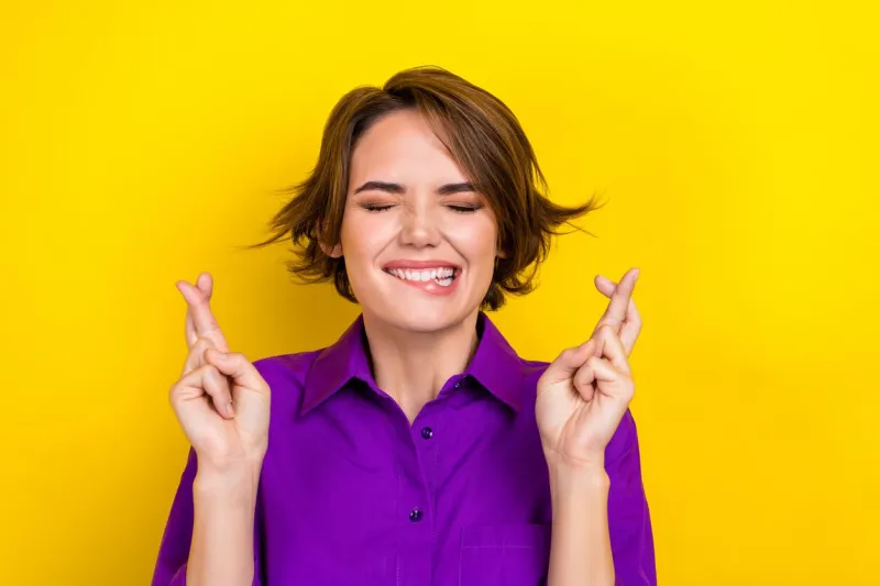 photo portrait of pretty young girl cross fingers close eyes dressed stylish purple smart casual outfit isolated on yellow color background