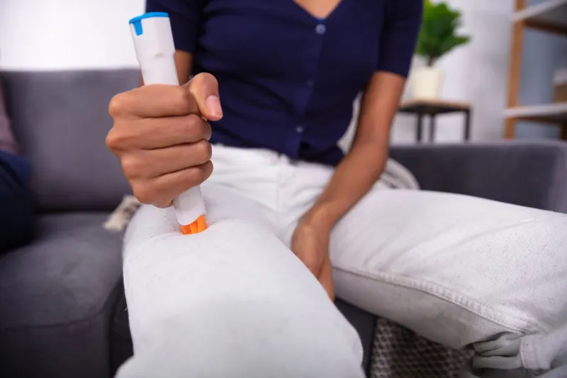 woman injecting epinephrine using auto-injector syringe as an emergency treatment for allergic reaction