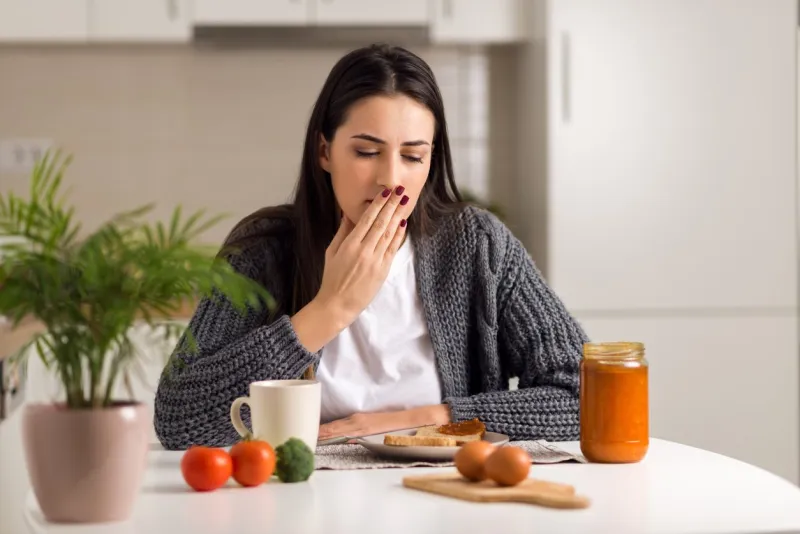 young woman feeling nausea during breakfast time at home