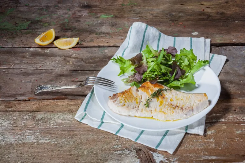 organic grilled swordfish steak and fresh salad on wooden table