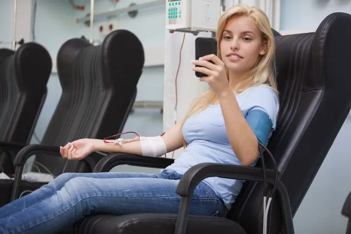 blonde woman relaxing in a chair while getting dialysis n hospital