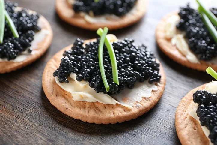 delicious cookies with black caviar on wooden table