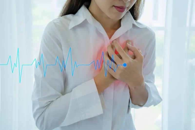 female who are suffering from acute heart disease using their hands holding their chest tightly wearing a white shirt on a white background, the incident occurred in her home