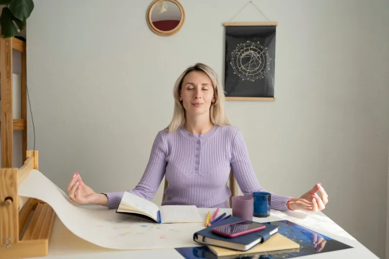 a girl meditates sitting at a table while working