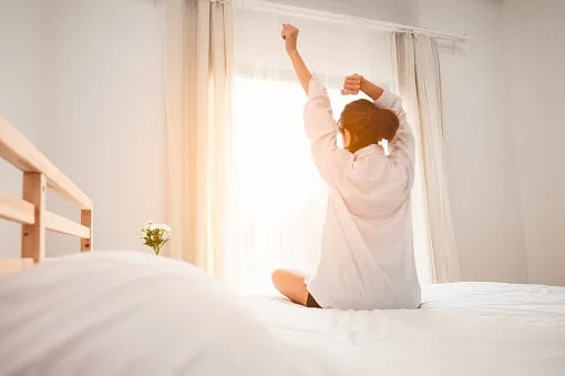 woman stretching in bed after waking up
