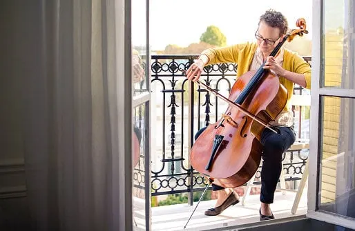 female classical musician playing cello on a balcony in paris