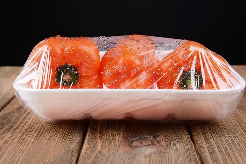 poivre emballé dans un film alimentaire sur table sur fond noir