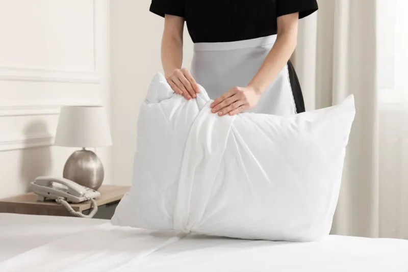 young maid making bed in hotel room, closeup