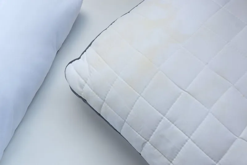 white pillows with yellow saliva stains and white new pillows on white backgroundtop view