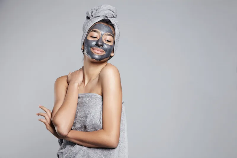 mixed race woman with clay coal grey facial cleansing mask treat