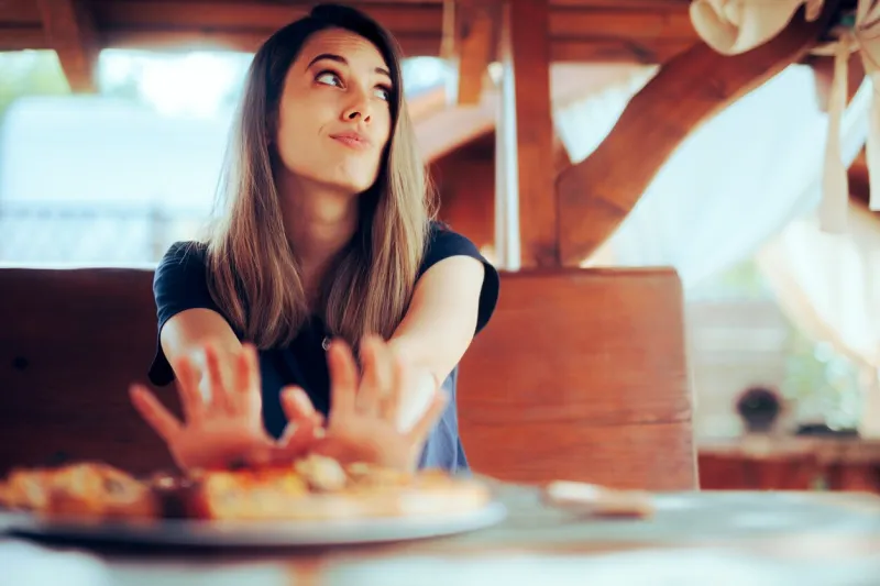 unhappy woman refusing to eat her pizza dish in a restaurant