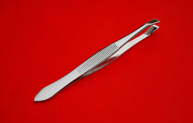 a pair of tweezers with a red background