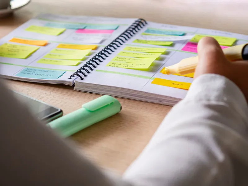 close-up of agenda organize with color-coding sticky notes for time management productive schedule for appointments and reminders hand holding a yellow highlighter marker organization and planning