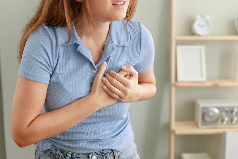 young woman pressing on chest with painful expression severe heartache, having heart attack or painful cramps, heart disease