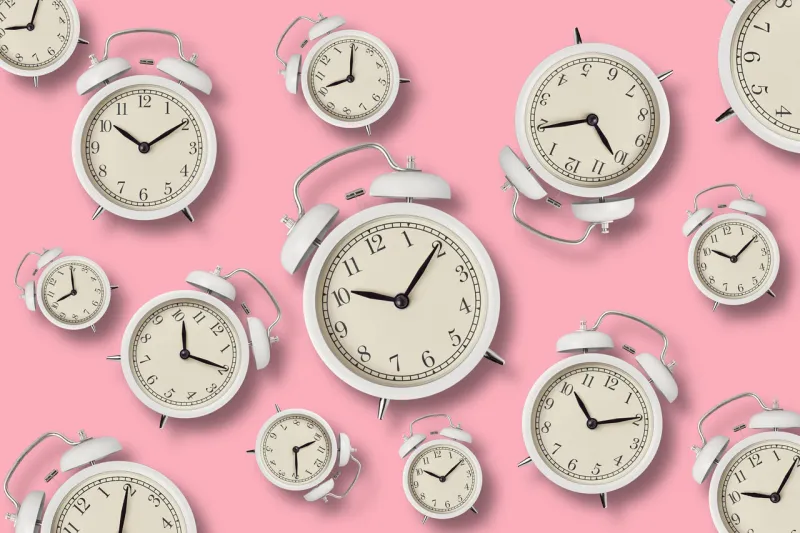 white vintage alarm clocks with shadows on pink background, top view minimal styly