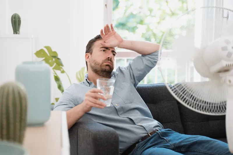 man refreshing with electric fan against summer heat wave