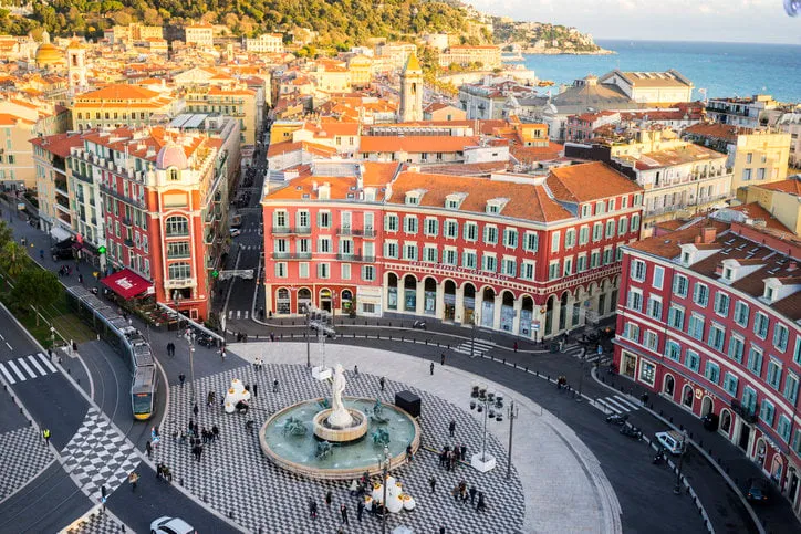 an aerial view of the fontaine du soleil in place messena, nice with the new tram track and buildings of nice and the sea in the background