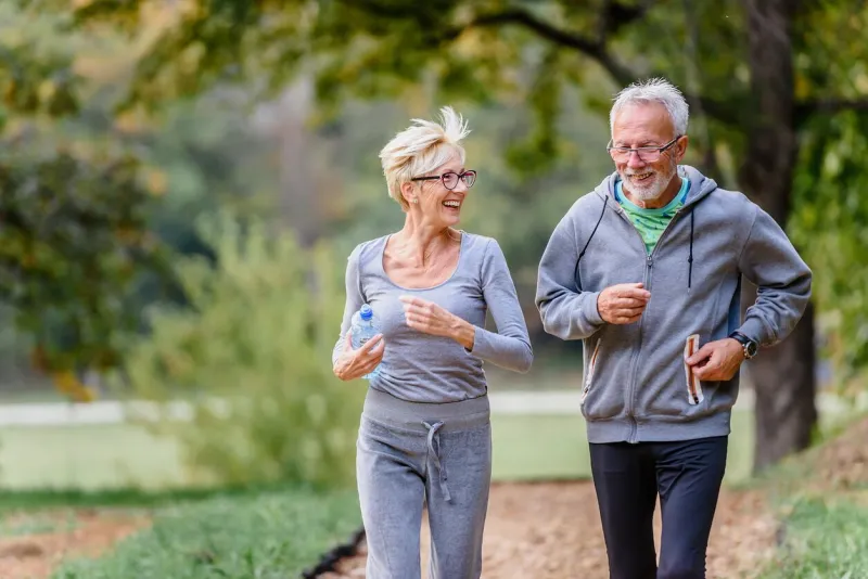 cheerful active senior couple jogging in the park exercise together to stop aging