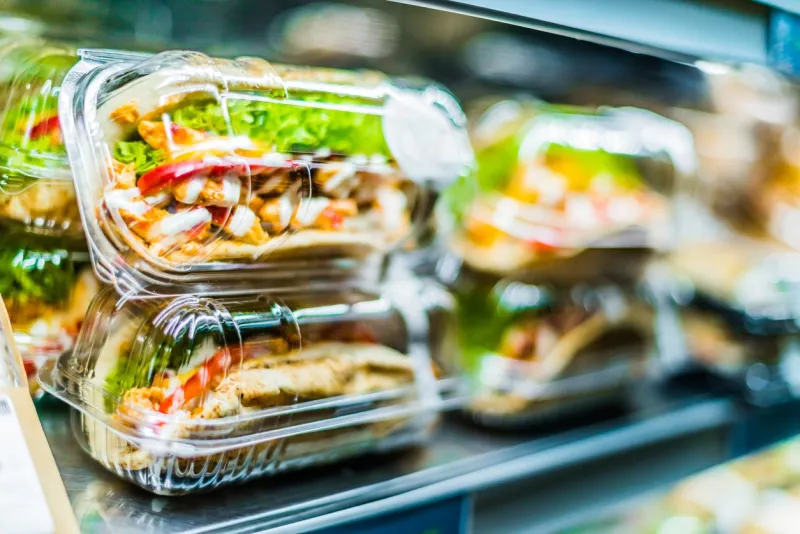chilli chicken with pita, pre-packaged sandwiches displayed in a commercial refrigerator