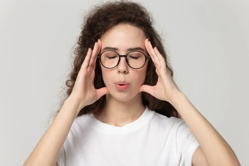 head shot close up portrait young tired woman in eyewear massaging temples, trying to reduce stress and calm down, breathing fresh air, isolated on grey white studio background, self-control concept