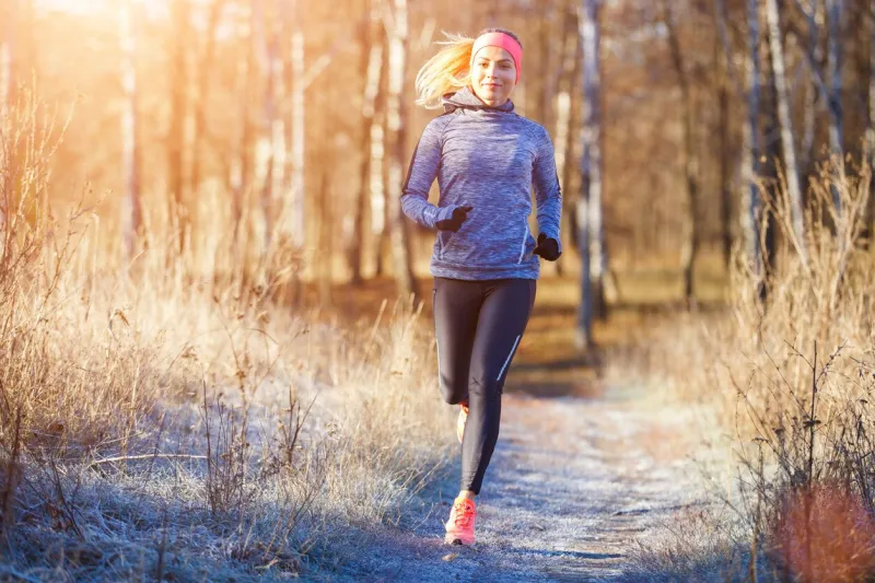 young slim girl running in the park in early winter attractive woman jogging on snowy trail