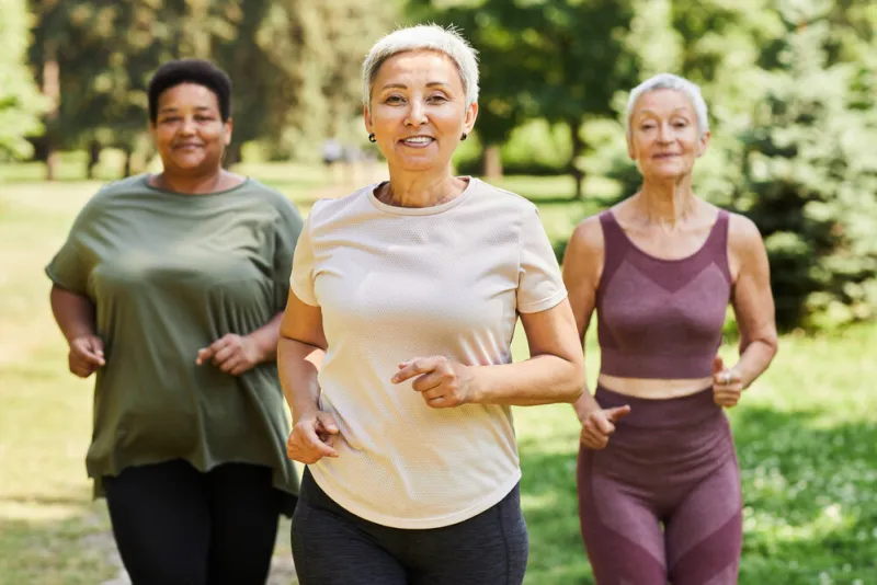 waist up portrait of active senior women running towards camera outdoors and enjoying sports