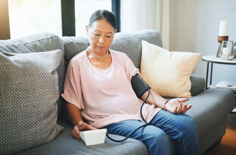 blood pressure, healthcare and senior woman in living room with equipment for hypertension sick, illness and elderly female person in retirement with medical tool in the lounge of modern home