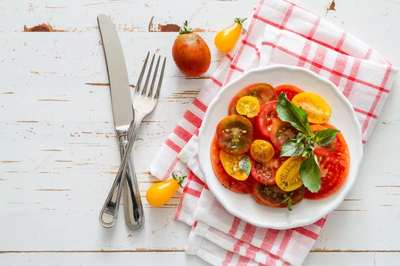 colorful tomato salad basil white plate on rustic wood background