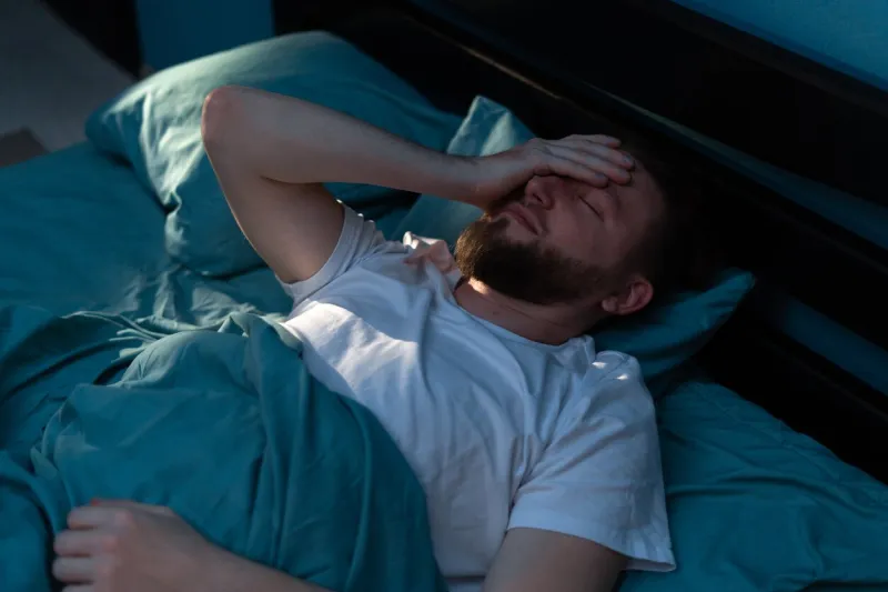 depressed millennial tired man awake in the night touching his forehead and suffering from insomnia copy space