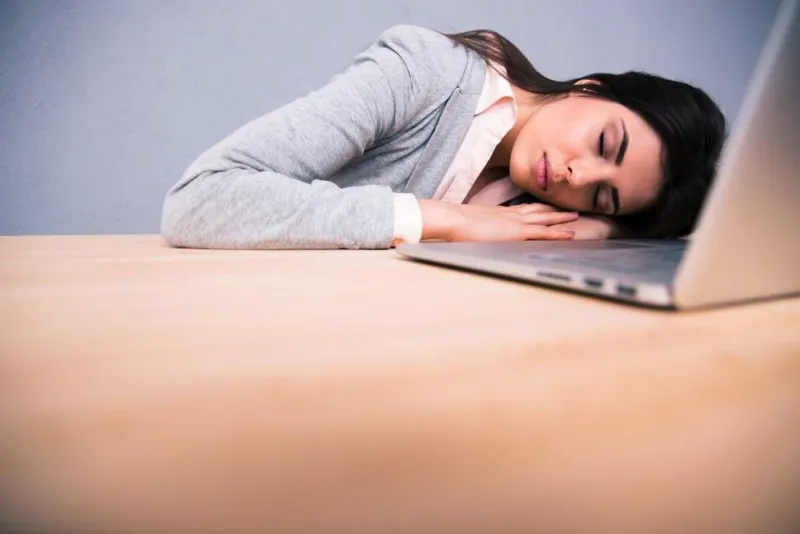 jeune jolie femme dormant sur la table avec un ordinateur portable