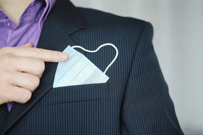 a disposable medical mask sticks out of a pocket instead of a napkin a man with a disposable mask in a suit and jeans individual respiratory protection