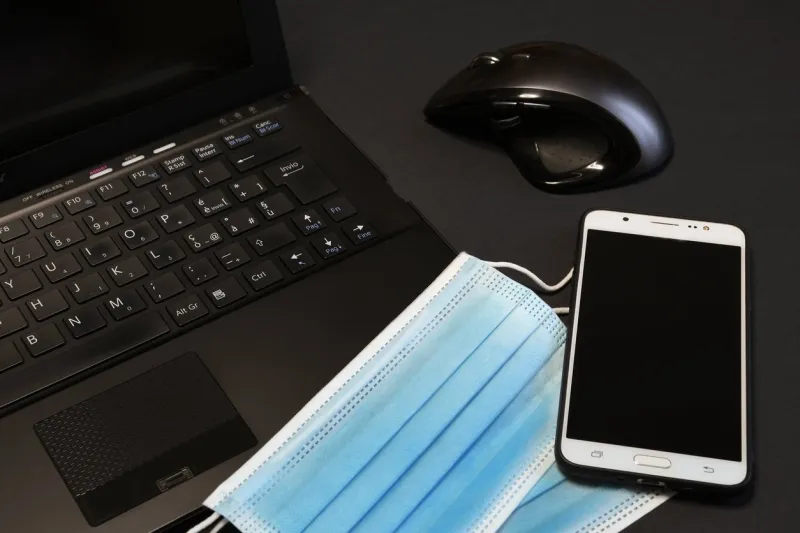 surgical face blue masks for coronavirus, covid-19 protection on notebook keyboard with mouse and smartphone work stay home concept of smart working