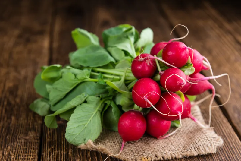 fresh radishes on wooden background (selective focus, close-up shot)