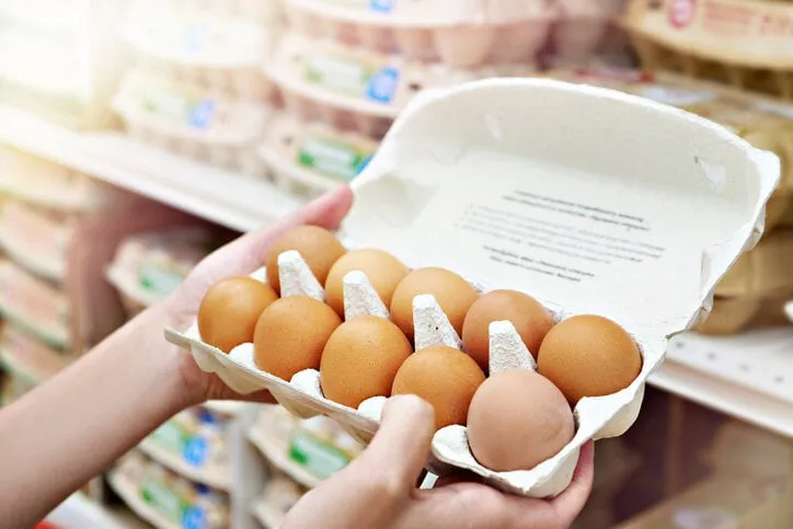 hands woman with packages of brown eggs in store