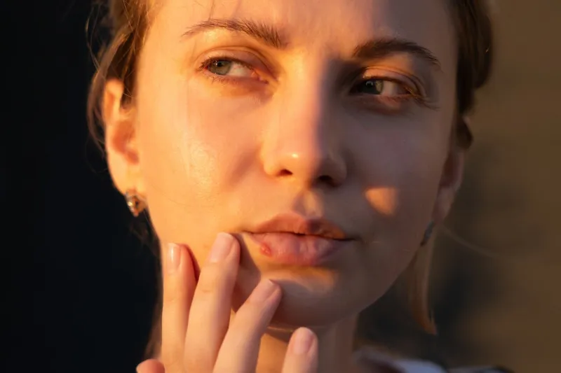 close up of girl's lips with herpes touching with a finger beauty dermatology concept
